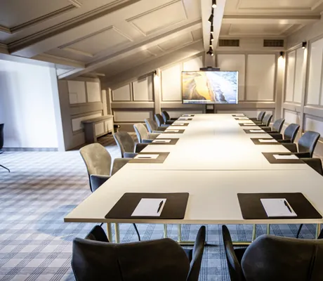 großer Tagungsraum im Das König Ludwig Inspiration SPA mit langem weißen Tisch und kariertem Teppich