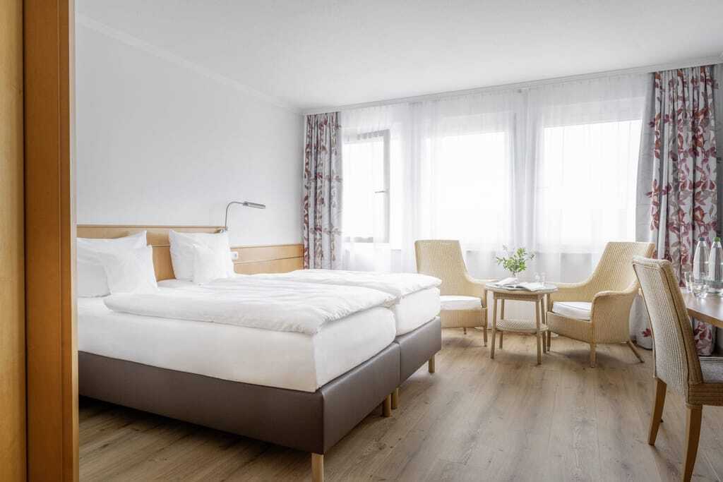 Zimmer im Hotel Krone Schnetzenhausen mit braunem Leder-Bettgestell und geblümten Vorhängen