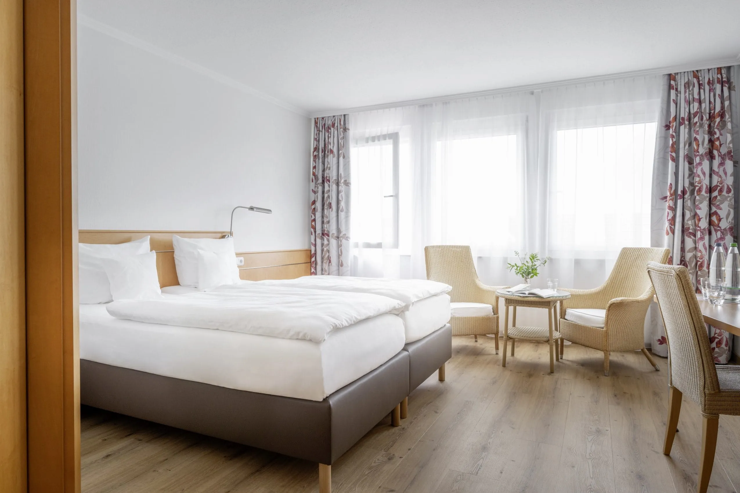 Zimmer im Hotel Krone Schnetzenhausen mit braunem Leder-Bettgestell und gebl&uuml;mten Vorh&auml;ngen