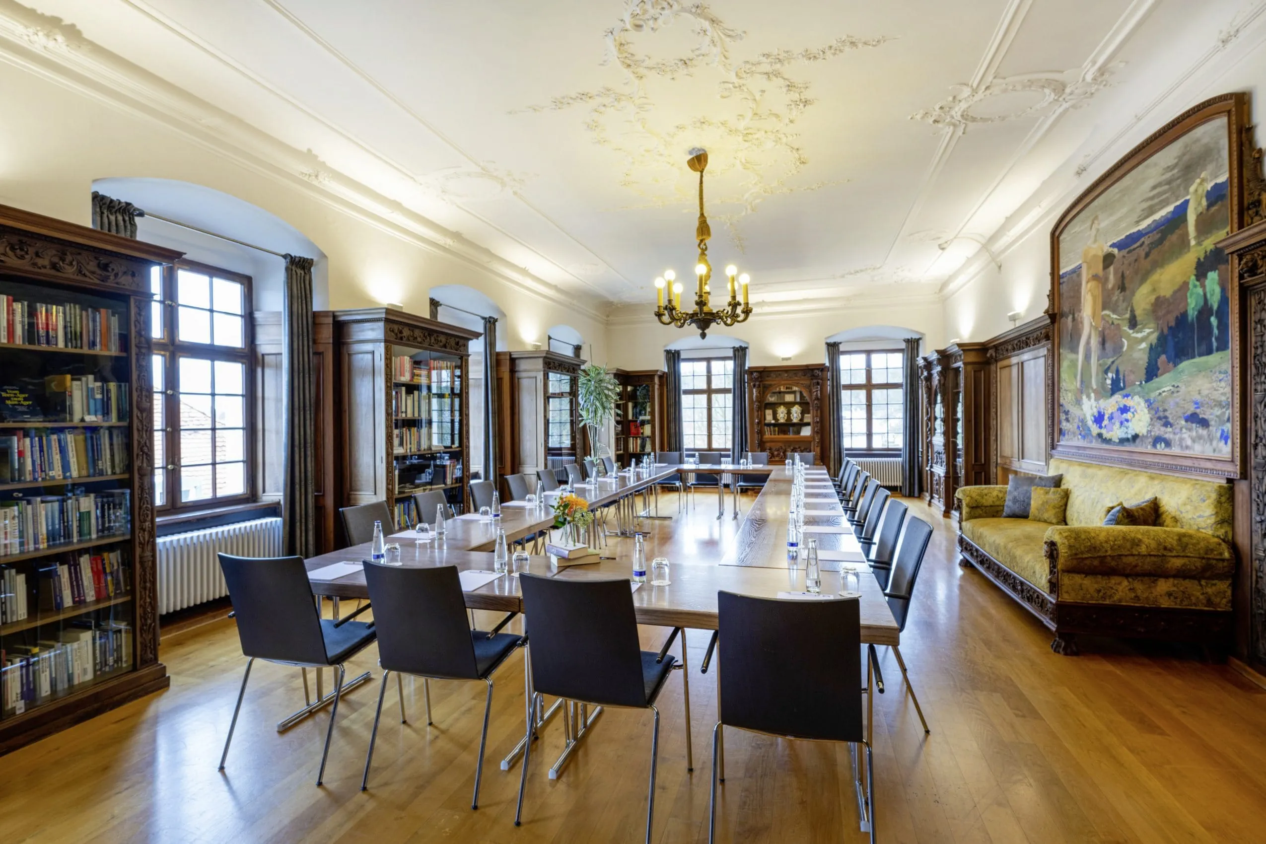 Tagungsraum in der Bibliothel des Schloss Lautrach mit altem Sofa und Kronleuchter