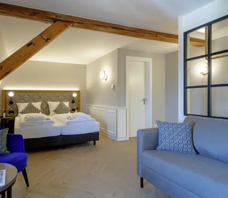Doppelzimmer im Schloss Lautrach mit schrägem Holzbalken und blauem Sofa