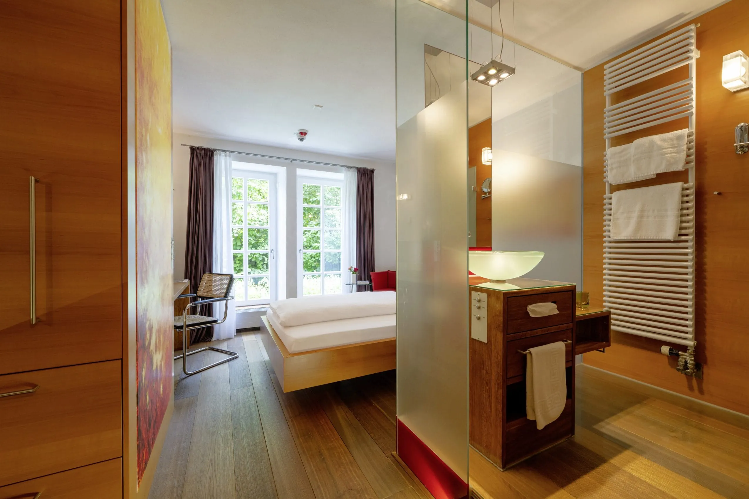 Zimmer im Schloss Lautrach mit Holzboden und Blick in das Bad mit rundem Waschbecken