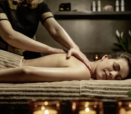 Frau wird von Masseurin in schwarzem Outfit auf der Liege im Spa des Hotel 47° massiert