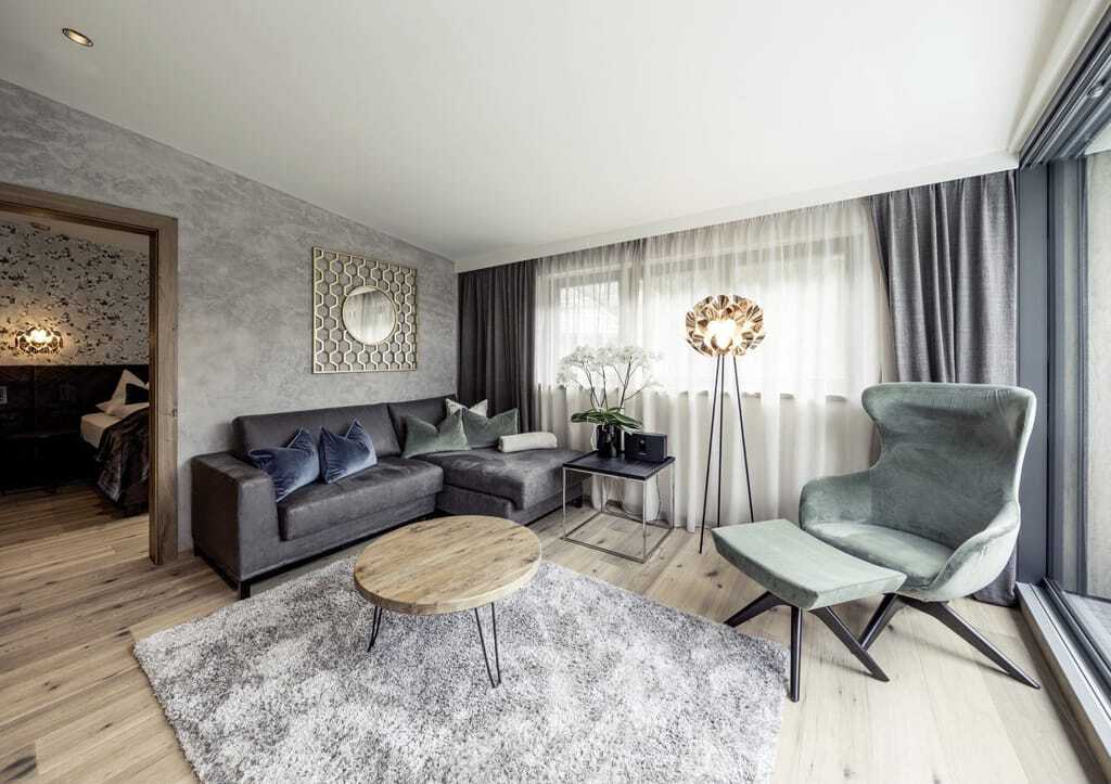 Suite im Alpenschlössel mit türkisem Ohrensessel und goldenem Ornament an der Wand