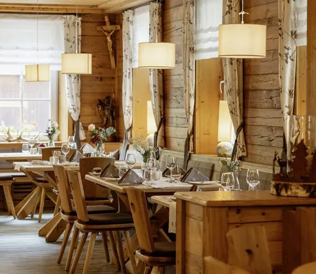 urige, rustikale Bühlerstube im Wellnesshotel Badischer Hof mit Holzmobiliar, gedeckten Tischen und runden Hängelampen