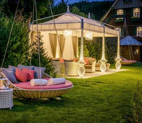 Liegewiese des Hotel Bareiss mit gemütlichen Hängeschaukeln und illuminiertem Pavillon mit Loungebereich