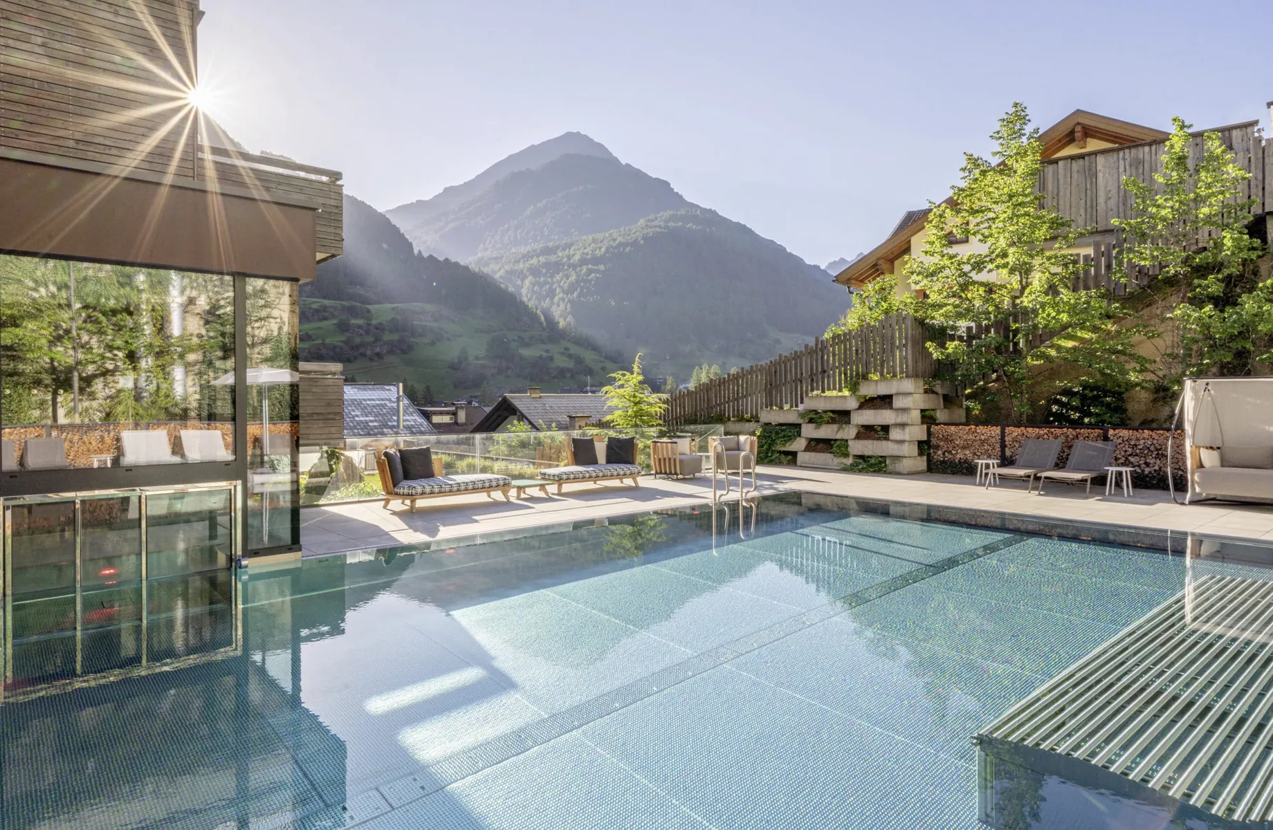 Outdoorpool im Bergland Sölden mit Whirlliegen und Blick auf die Berge