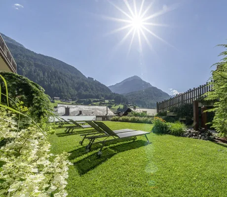 Garten des Bergland Sölden mit Liegen vor dem Zaun bei strahlendem Sonnenschein