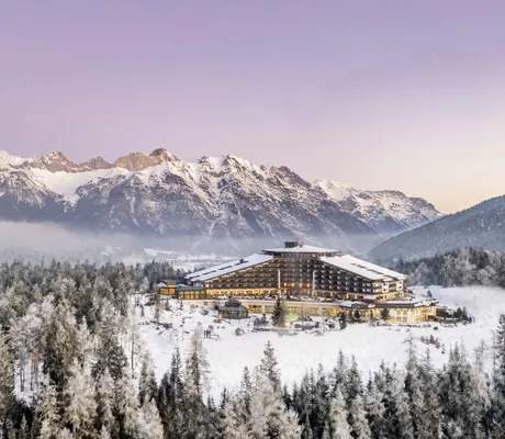 Außenansicht des Interalpen-Hotel Tyrol im Winter mit Bergen im Hintergrund