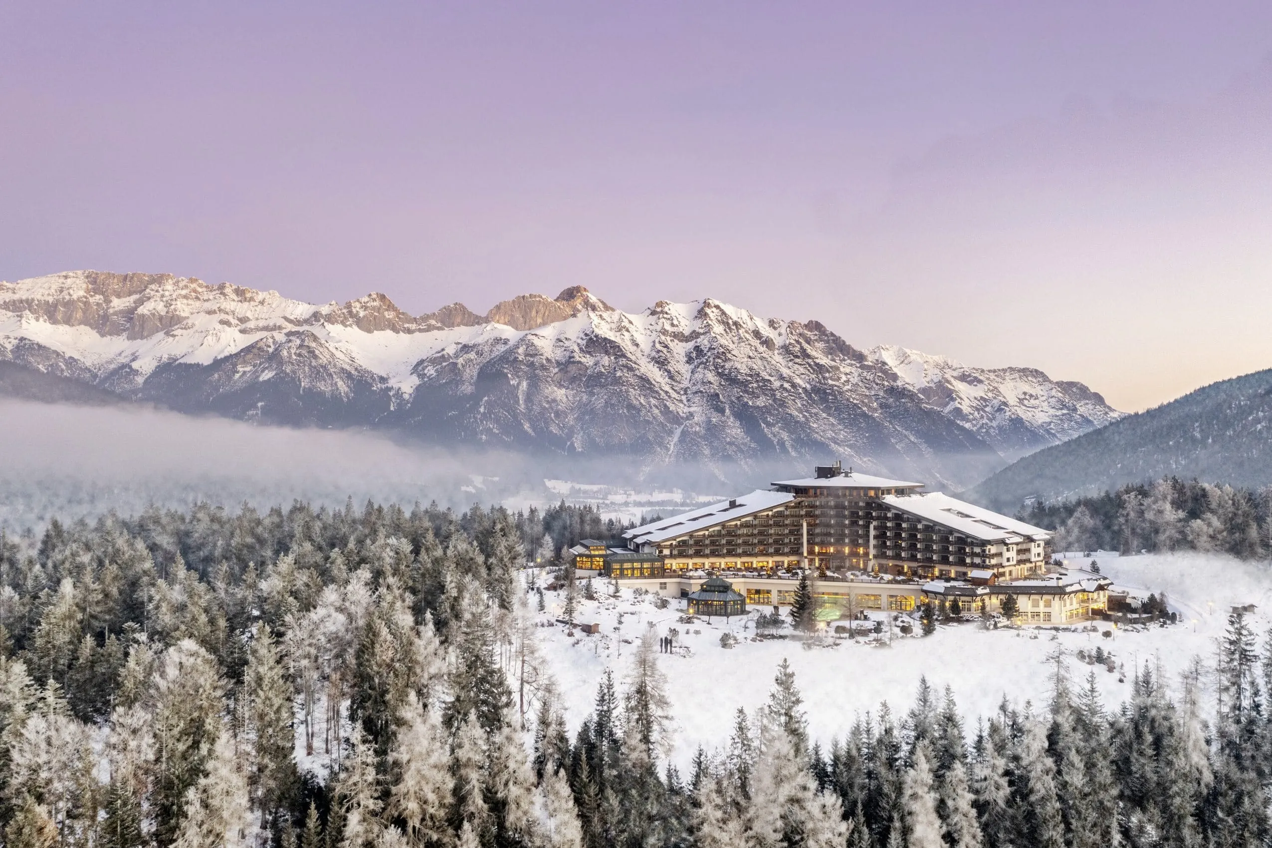 Außenansicht des Interalpen-Hotel Tyrol im Winter mit Bergen im Hintergrund