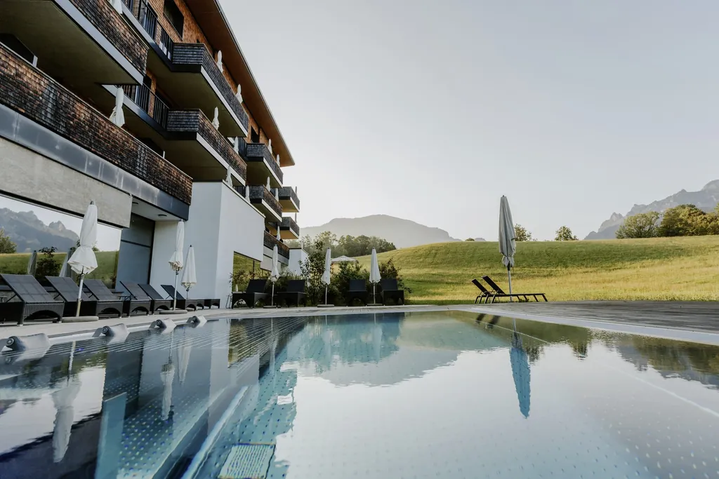 Outdoorpool des Klosterhof - Alpine Hideaway & Spa mit Blick auf die Wiese vor dem Hotel
