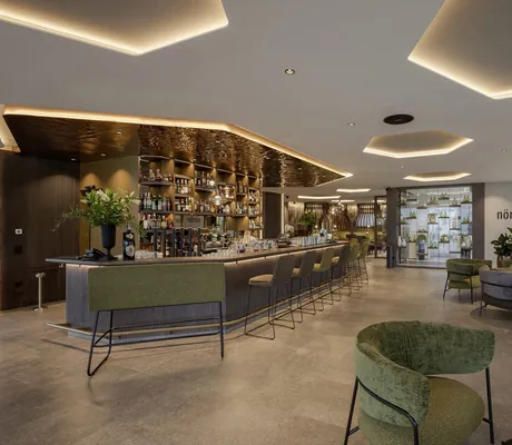 Bar im La Maiena Meran Resort mit grünen Hochstühlen und sechseckigen großen Deckenlampen