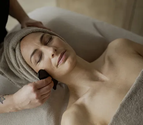 Frau wird auf Kosmetiklieg im Spa des La Maiena Meran Resort mit Gua Sha behandelt