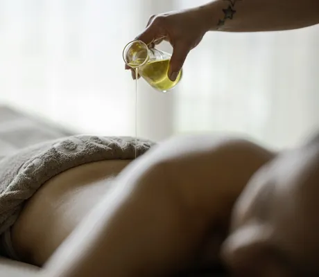 aus einer Glaskaraffe wird Öl im La Maiena Meran Resort auf den Rücken einer Frau gegossen