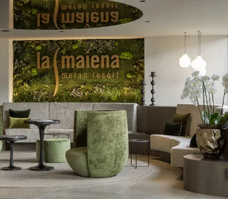 grüne Hochlehner und eine bepflanzte Logowand im Eingangsbereich des La Maiena Meran Resort