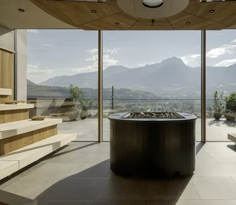 große Sauna mit mittig platziertem Ofen und Blick auf Meraner Land im La Maiena Meran Resort