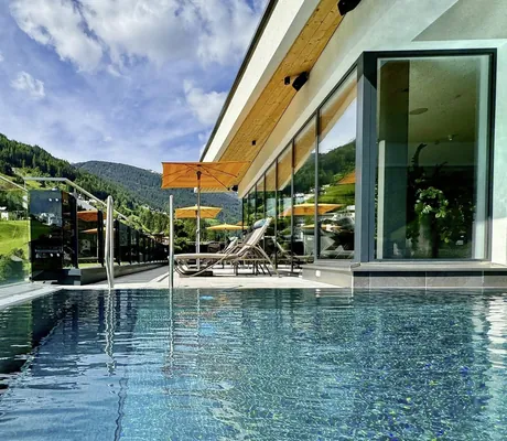 Outdoorpool im SeeMOUNT - Active Nature Resort mit gelben Sonnenschirmen und Blick auf hügelige Wiesen