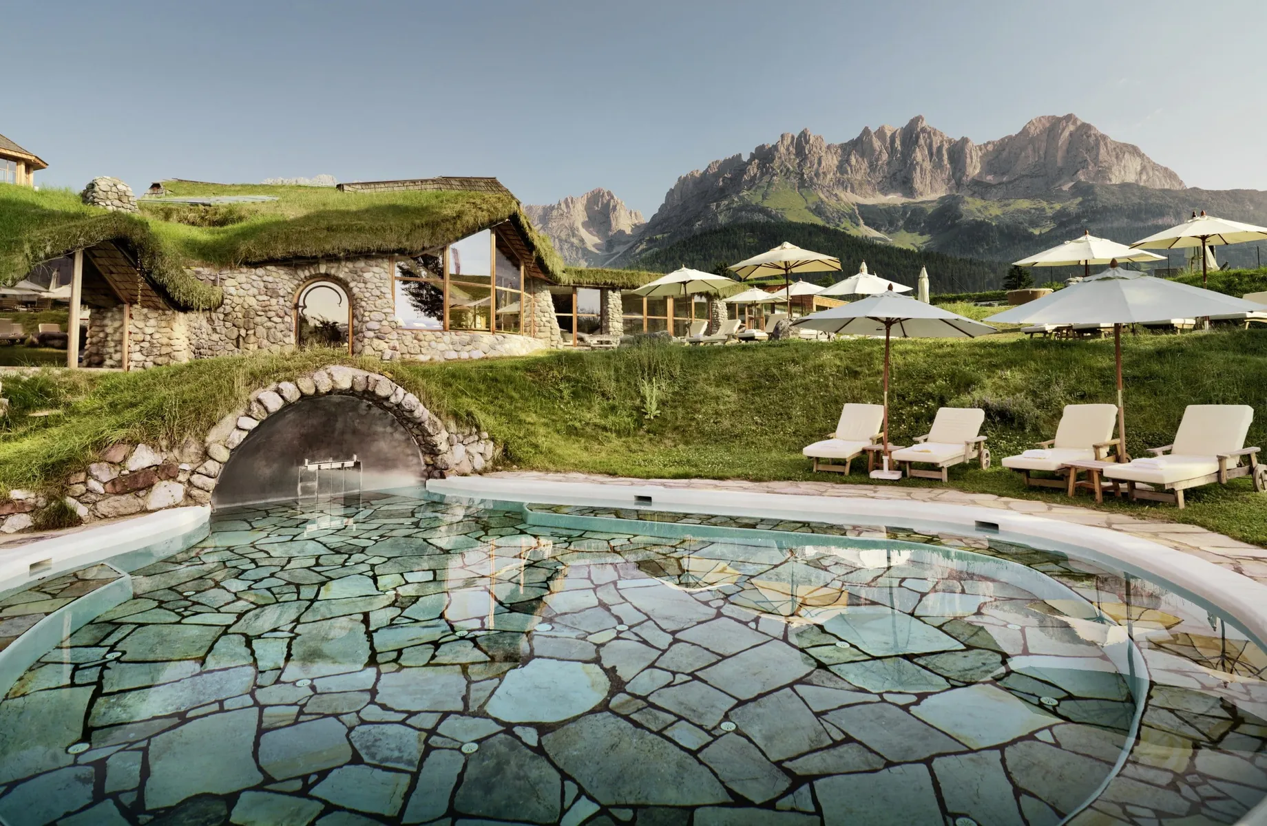 runder Outdoorpool im Bio- & Wellnessresort Stanglwirt mit verschieden großen türkisen Fliesen und Blick auf den Wilden Kaiser