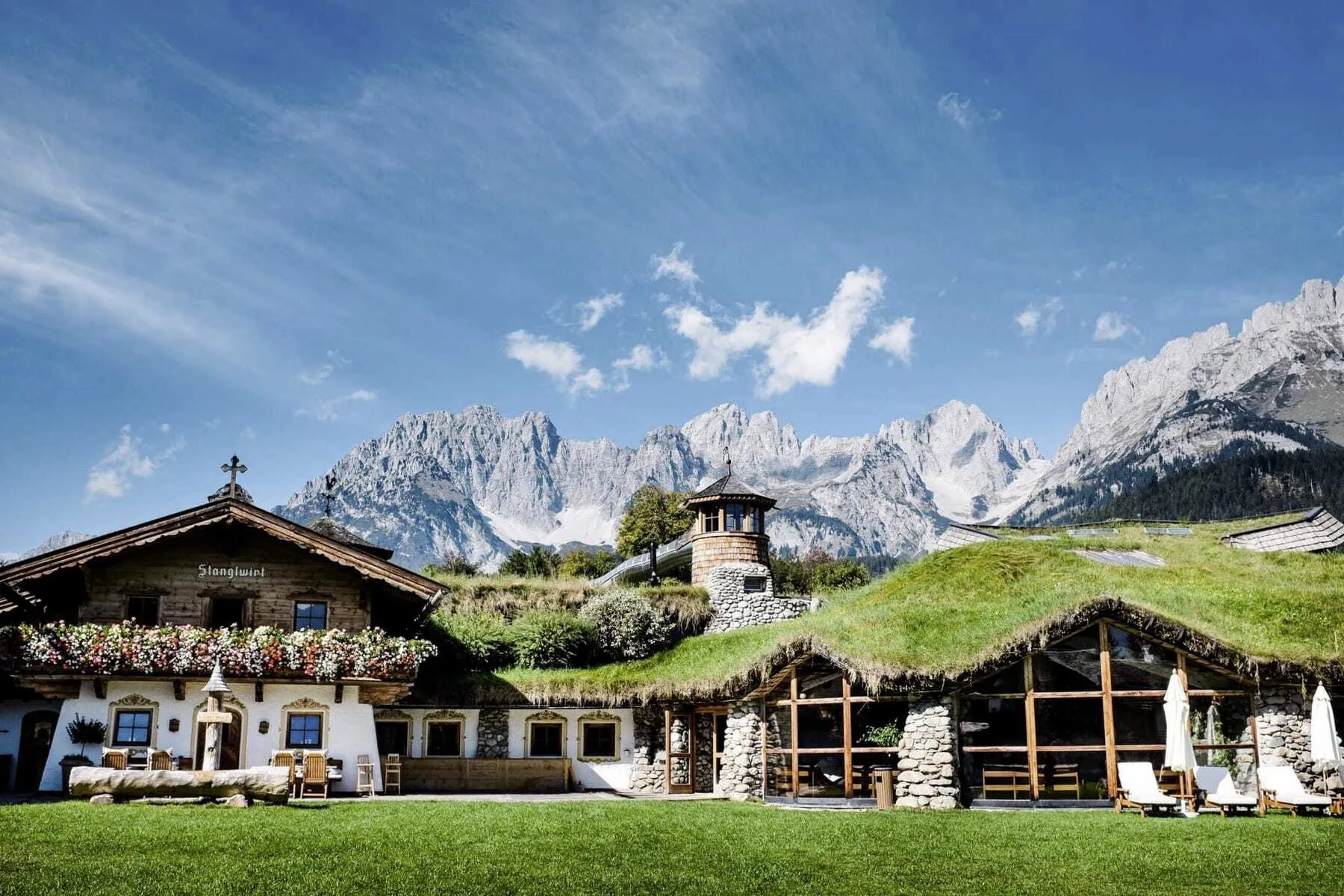 Wiese vor dem Eingang des Bio- & Wellnessresort Stanglwirt mit begrüntem Dach und Blick auf den Wilden Kaiser