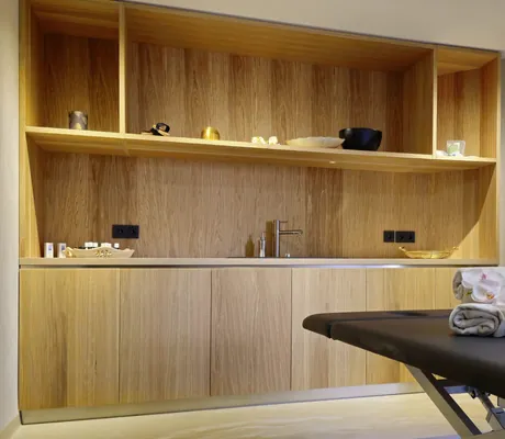 Behandlungsraum im Hotel Waldblick Kniebis mit schwarzer Liege und großem Holzregal