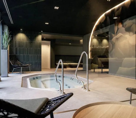 Wellnessbereich des Wellnesshotel Wittelsbach mit Whirlpool, schwarzen Sesseln und sanfter Beleuchtung