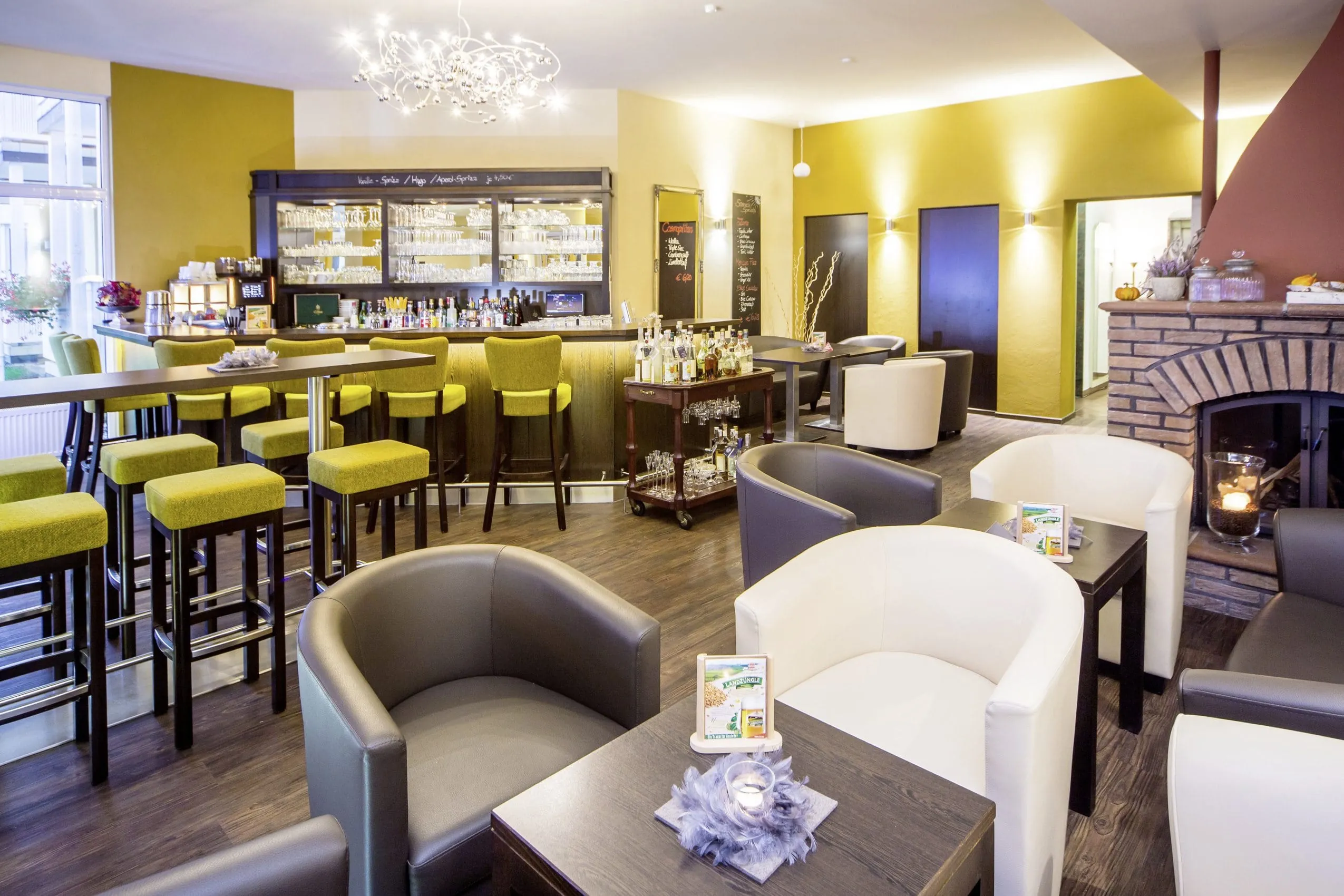 Gemütliche Bar-Lounge mit modernen, farbenfrohen Sitzgelegenheiten, einer gut ausgestatteten Theke, und einem einladenden Kamin, der eine warme Atmosphäre schafft.