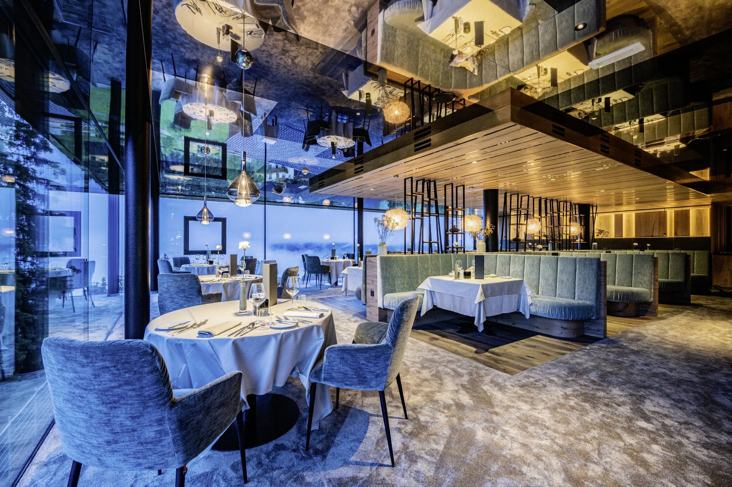 stylisches Restaurant mit türkisen Sitzmöbeln und Designerlampen im Alpen Tesitin