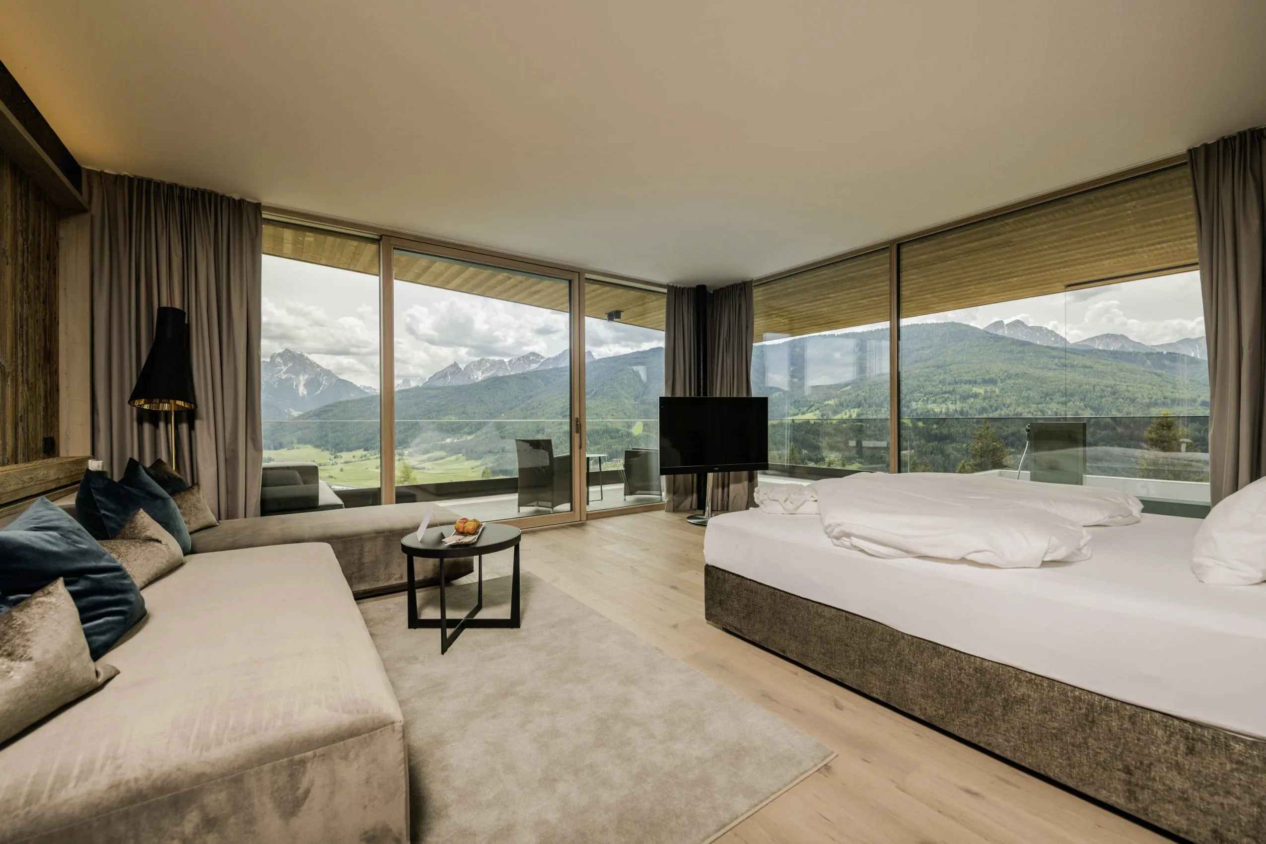 Zimmer im Alpen Tesitin mit naturfarbenen Couches und Balkonblick auf die Berge