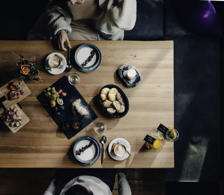 Gedeckter Frühstückstisch in den Südtirol Chalets Valsegg von oben mit Brötchen, Croissants, Früchten, Käse und mehr