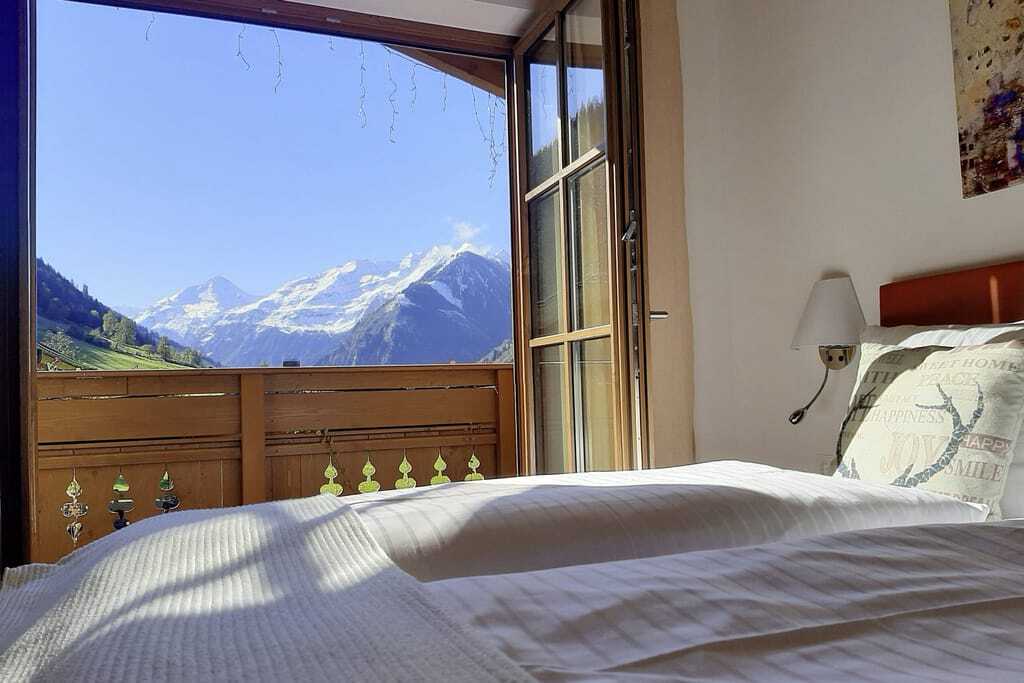 Blick vom Doppelbett der Hochalmbahnen Chalets auf die Berge bei blauem Himmel