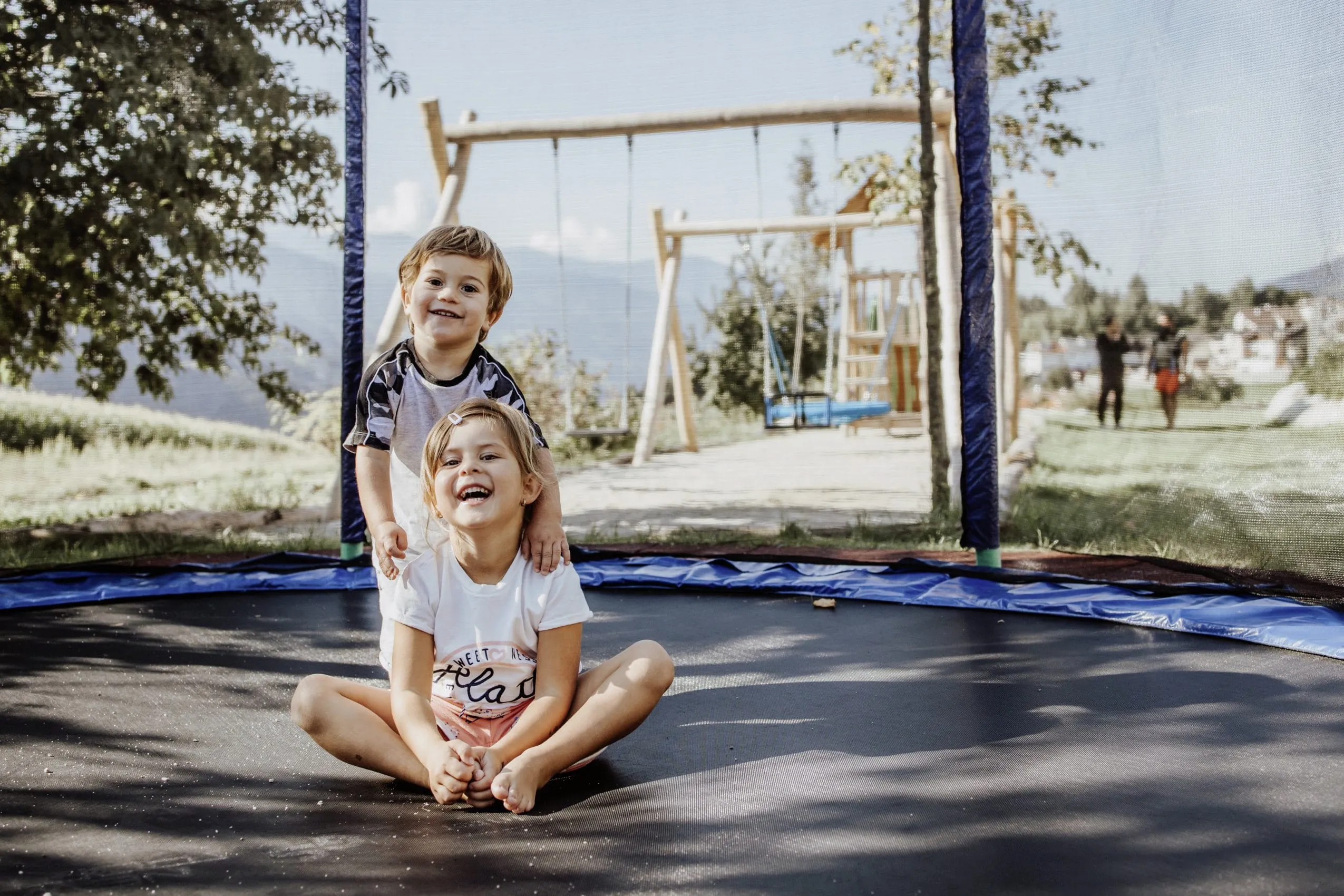 Junge und Mädchen sitzen auf dem Trampolin im Das Mühlwald Quality Time Family Resort