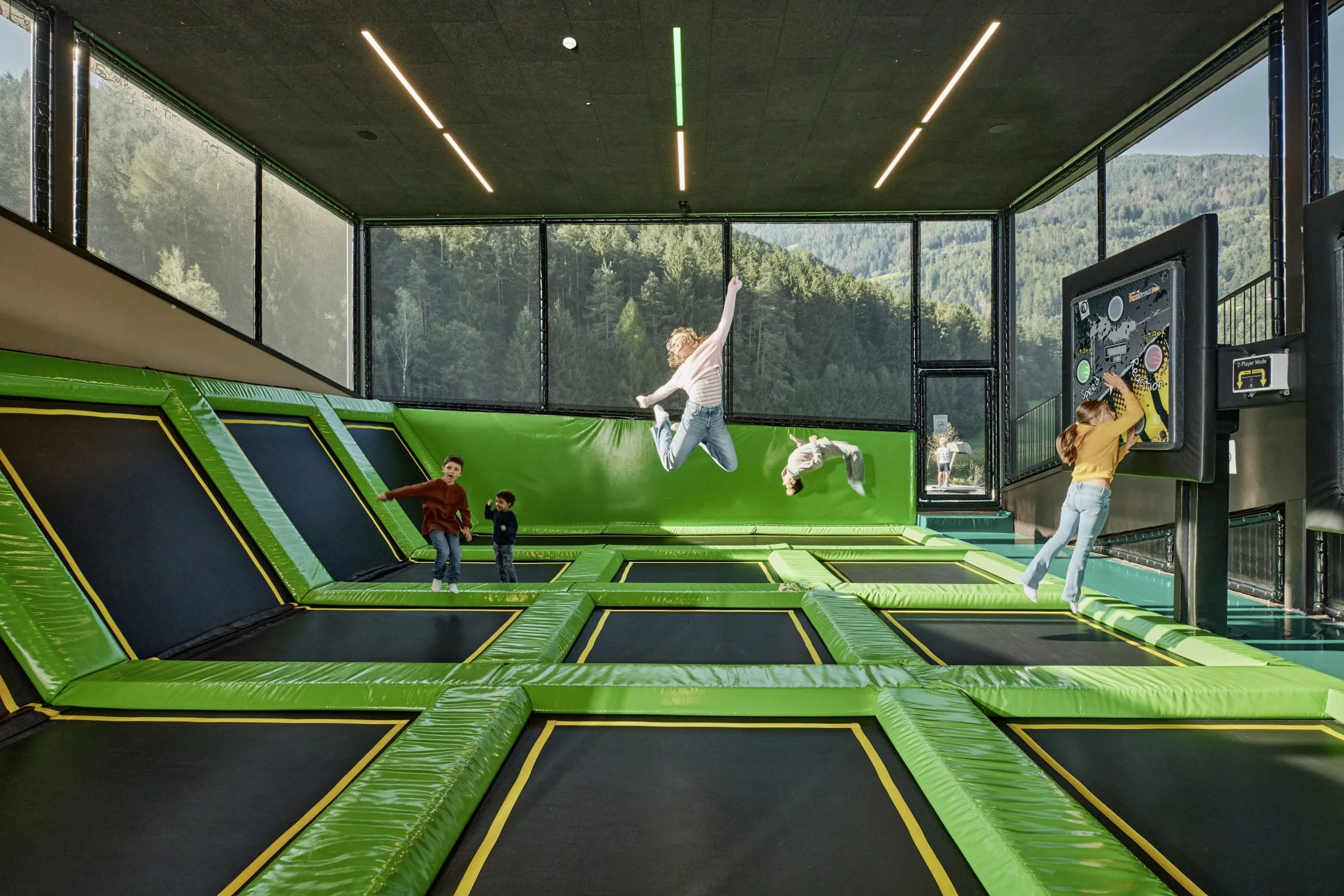 Kinder springen auf Valojump Trampolinanlage mit grünen Kissen im Falkensteiner Family Resort Lido