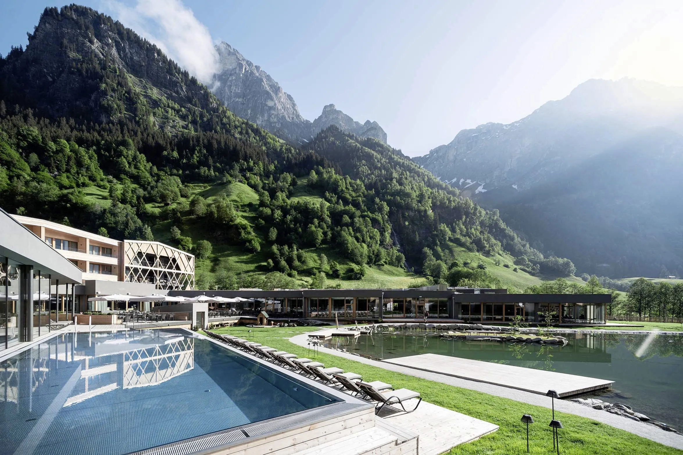 Außenbereich des Feuerstein Nature Family Resort mit Naturbadeteich und Outdoorpool mit Blick auf die Berge