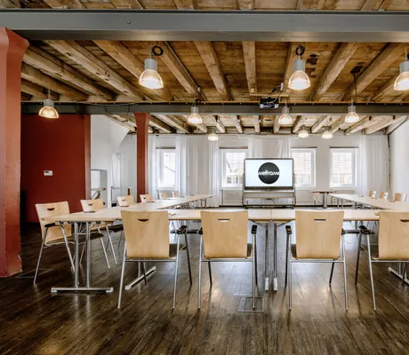 Tagungsraum des Hotel Speidel’s BrauManufaktur mit Bestuhlung in U-Form, Bildschirm im Hintergrund und Holzdecke