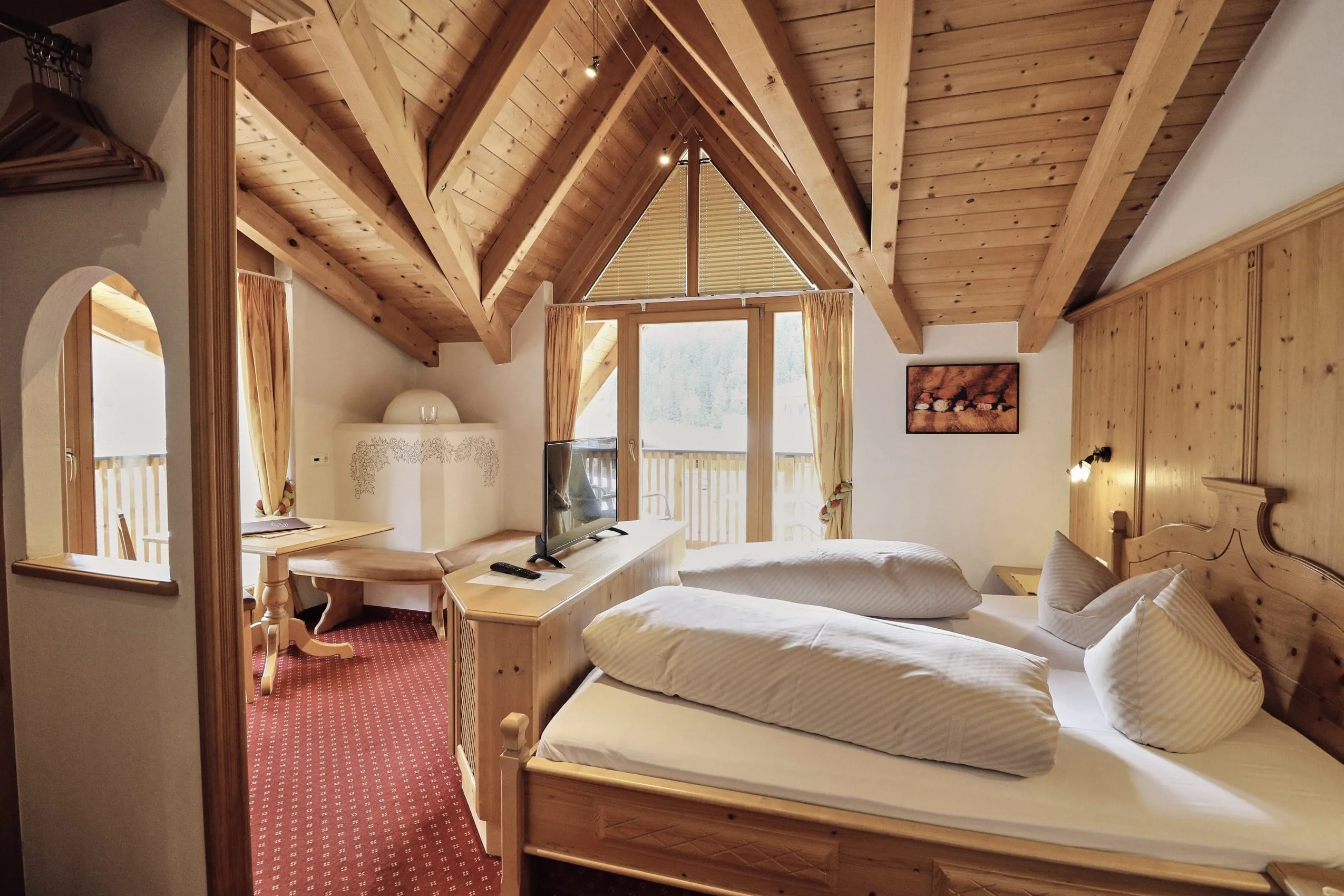 Giebelzimmer im Hotel Traube mit Holzwand hinter dem Bett und wei&szlig;em Kamin