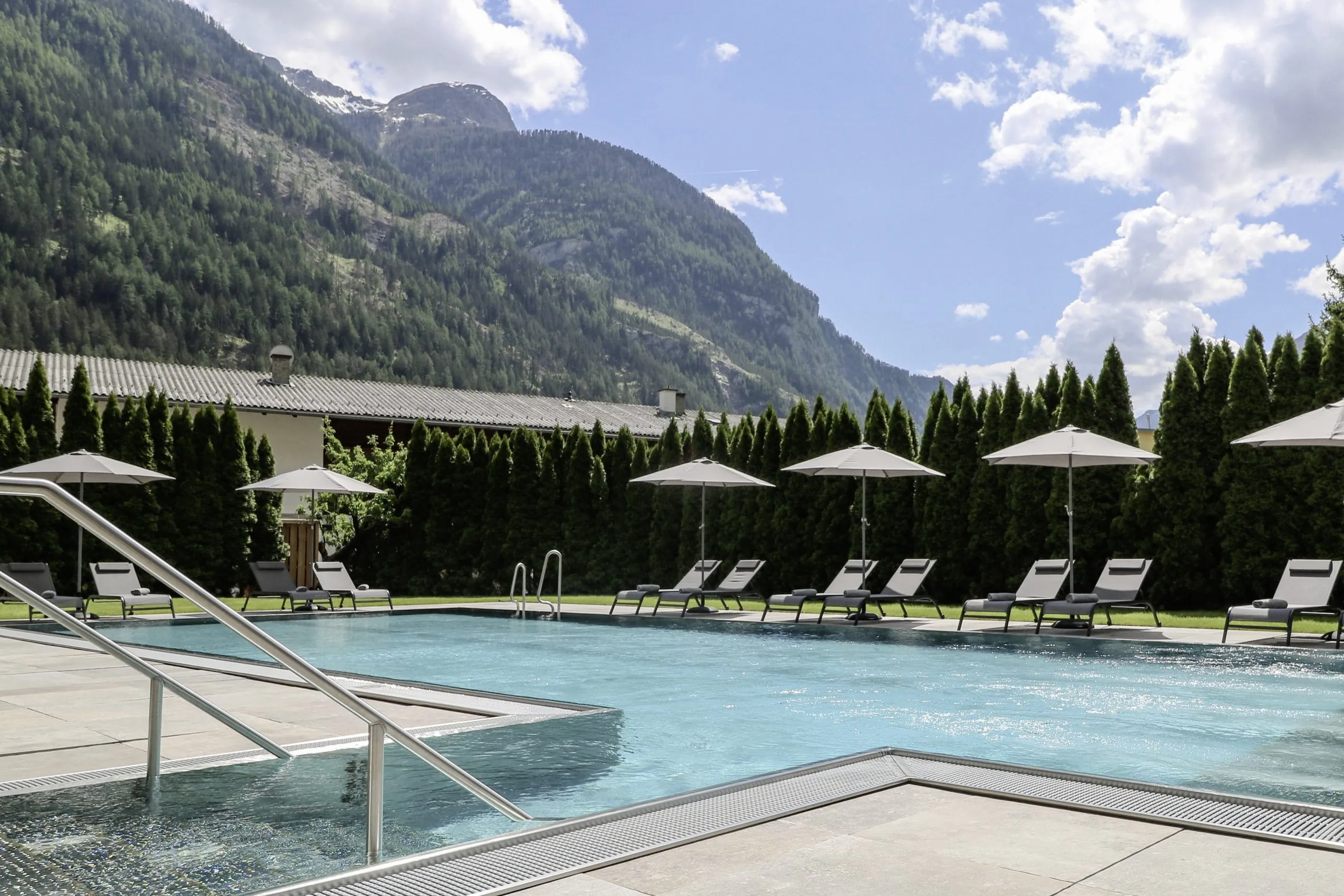 Outdoorpool im Hotel Traube mit wei&szlig;en Sonnenschirmen und Blick auf die Berge