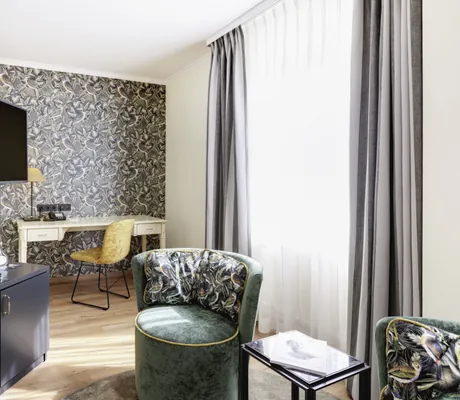 Zimmerausschnitt mit samtenem Sessel und gemusterter Vogeltapete im Best Western Hotel Rebstock