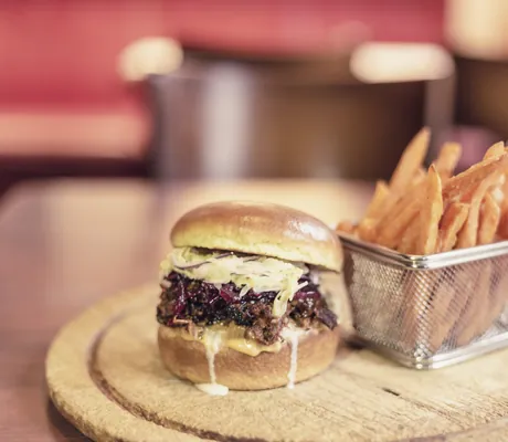 Burger mit Kraut und Pommes auf einem Brett im Hotel Das Ebertor