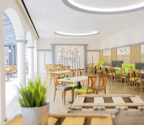 Restaurant mit grünen und grauen Stühlen mit Lichtinstallation an der Wand im Hotel Das Ebertor