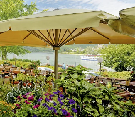 Terrasse des Hotel Das Ebertor mit großem beigem Sonnenschirm und Blick auf den Rhein