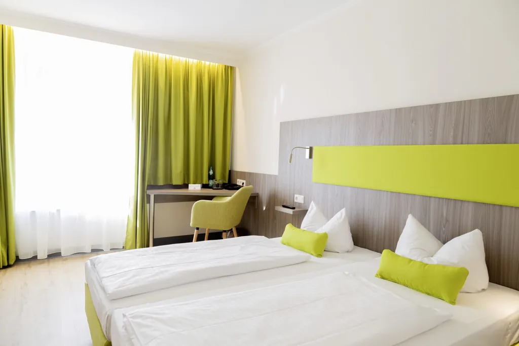 Komfortzimmer im Hotel Das Ebertor mit grünem Stoff-Bettkopf und lindgrünem Sessel