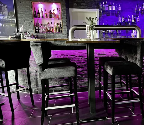 lila beleuchteter Tresen an der Bar im Parkhotel Fasanerie mit dunklen Hochstühlen