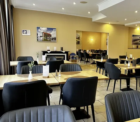 Restaurant im Parkhotel Fasanerie mit gelben Wänden und Esstischen mit schwarzen Stühlen