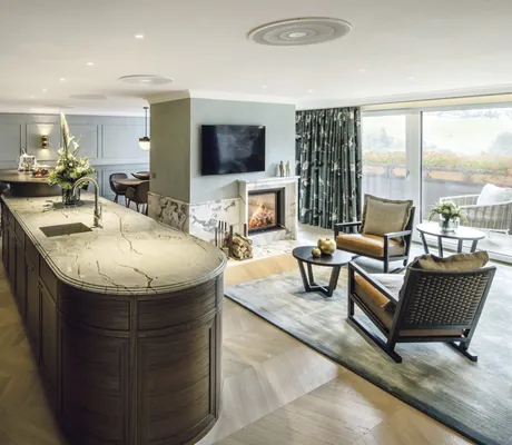 Elegantes Wohn- und Esszimmer einer Suite im Hotel Bareiss mit offener Küche, Kamin, moderner Einrichtung und großer Fensterfront mit Ausblick