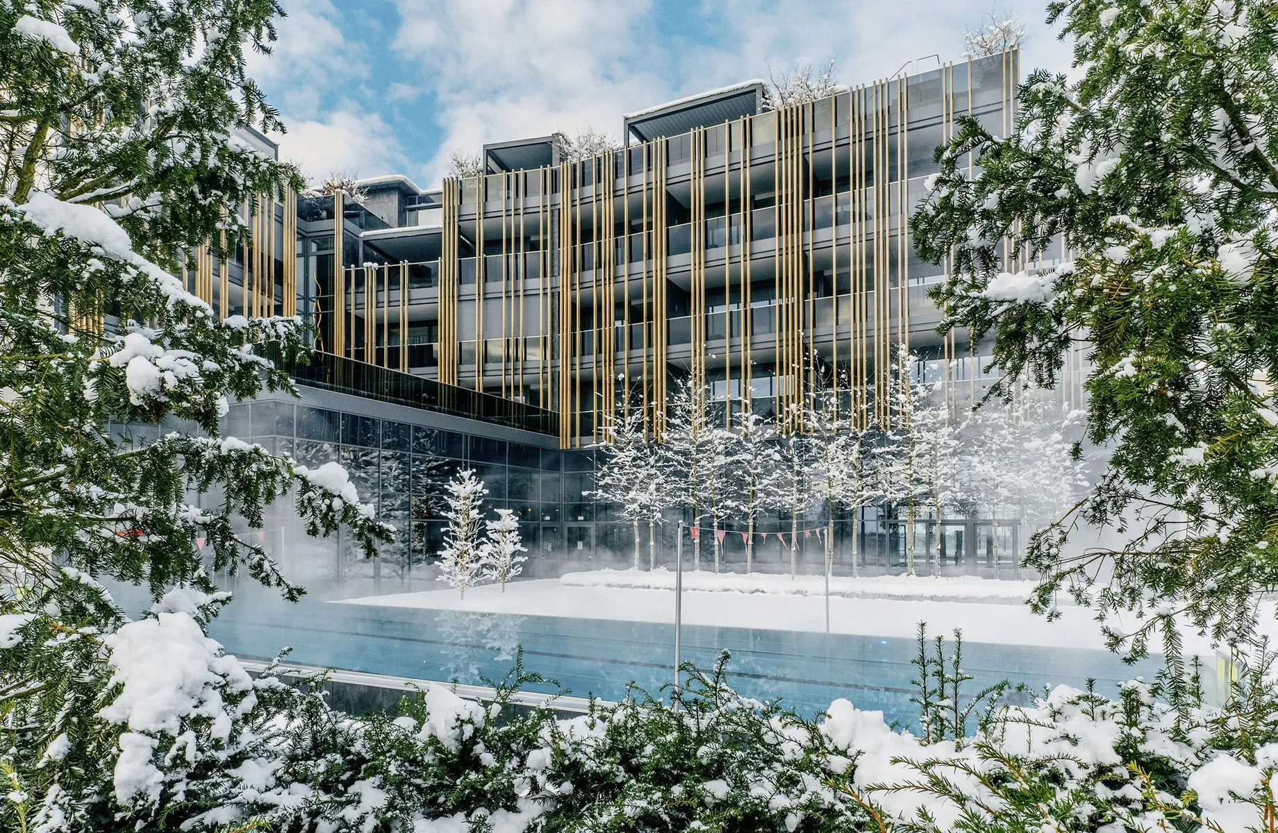 Fassade Wellnesshotel Jagdhof hinter Außenpool im tiefen Schnee