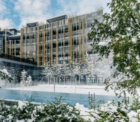 Fassade Wellnesshotel Jagdhof hinter Außenpool im tiefen Schnee