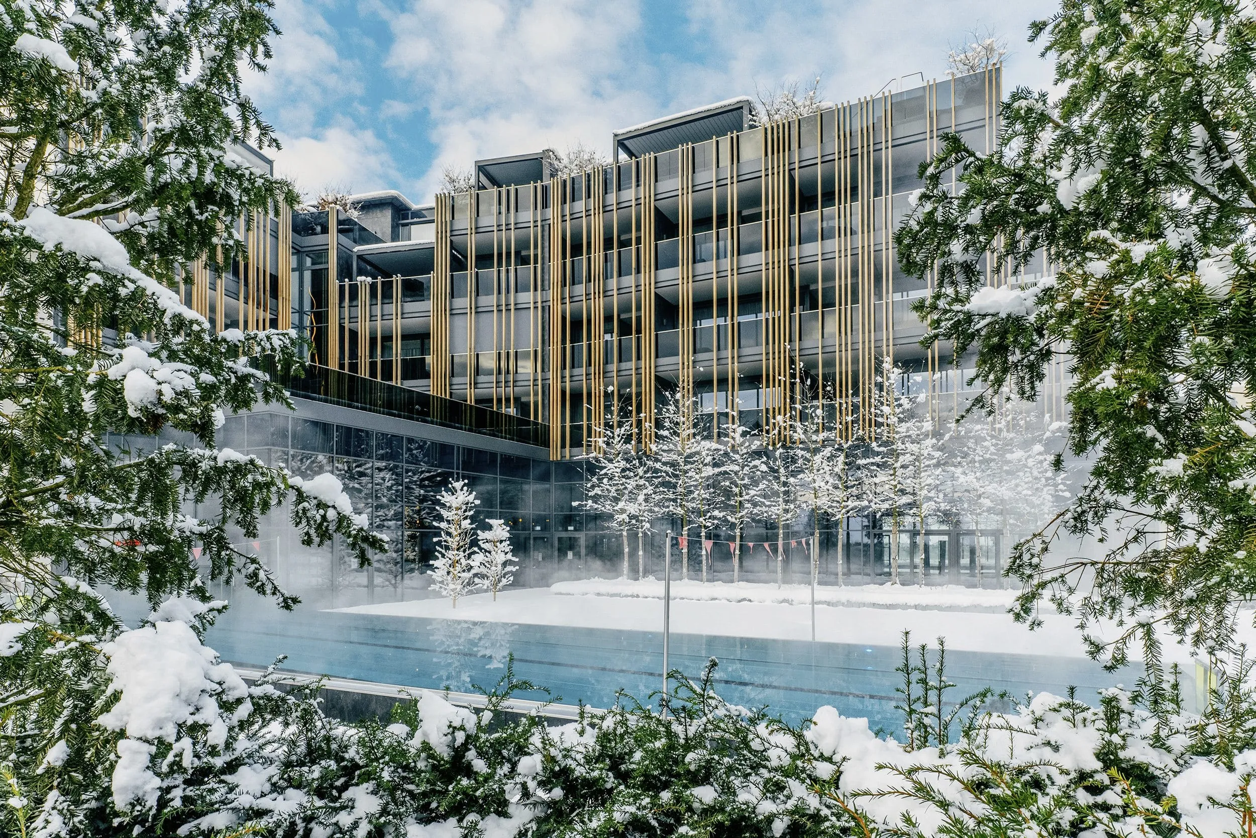 Fassade Wellnesshotel Jagdhof hinter Außenpool im tiefen Schnee