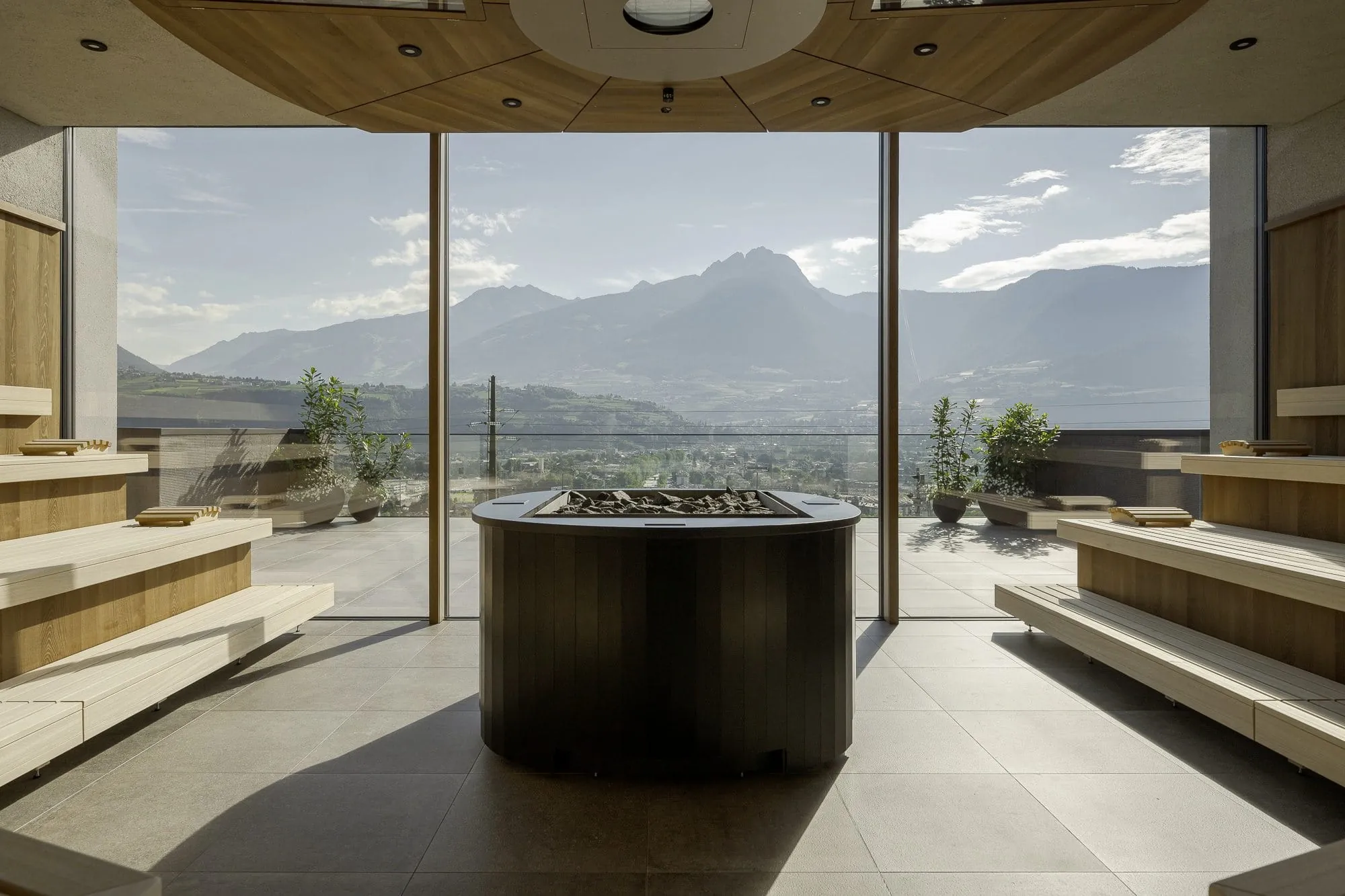 Sauna im La Maiena mit großem Saunaofen in der Mitte und Blick auf Meran