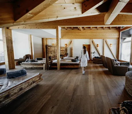 Frau in weißem Bademantel im Ruhebereich des Hotel Post Seefeld mit Altholzliegen