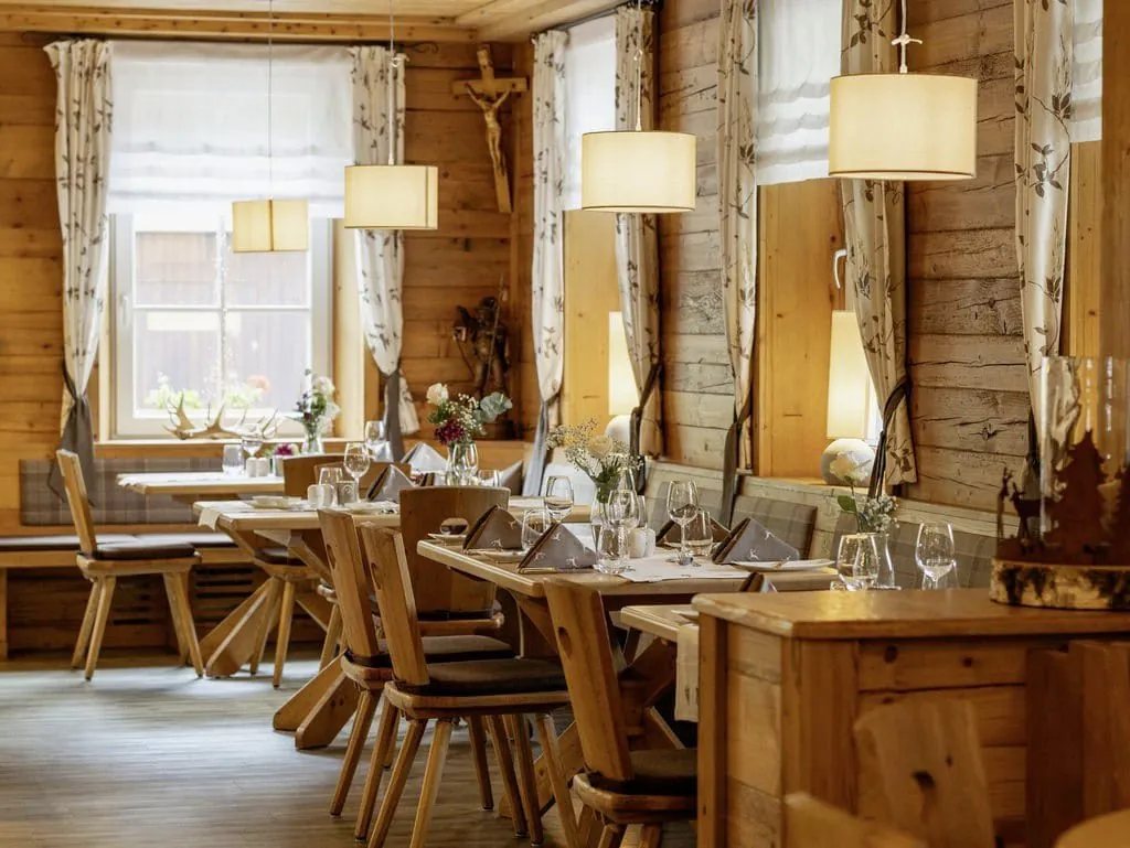 urige, rustikale B&uuml;hlerstube im Wellnesshotel Badischer Hof mit Holzmobiliar, gedeckten Tischen und runden H&auml;ngelampen